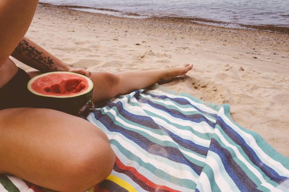 person eating watermelon by the beach